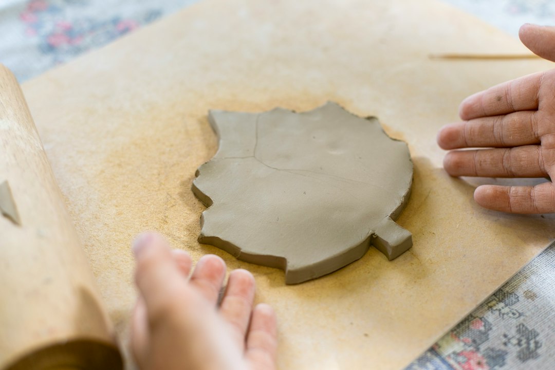 Mains d’une céramiste façonnant une pièce sur le tour dans l’atelier Sillage